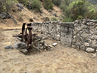 Historic mill waterwheel on display next to millhouse ruins. 
